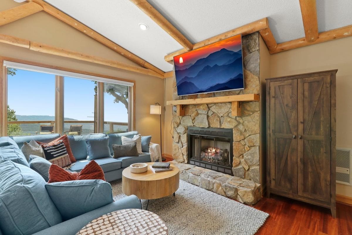 Unwind in the cozy mountain-view living room featuring a stone fireplace, smart TV, and plush sectional seating—perfect after a day on Beech Mountain, just 5 minutes away.